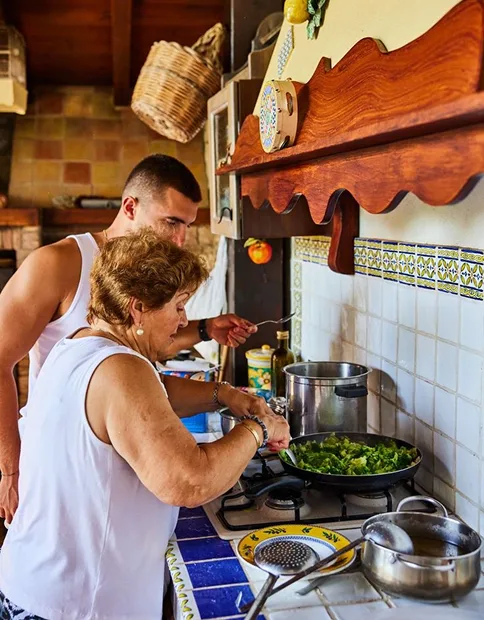 A grandmother and her grandson cooking together in a tiled home kitchen